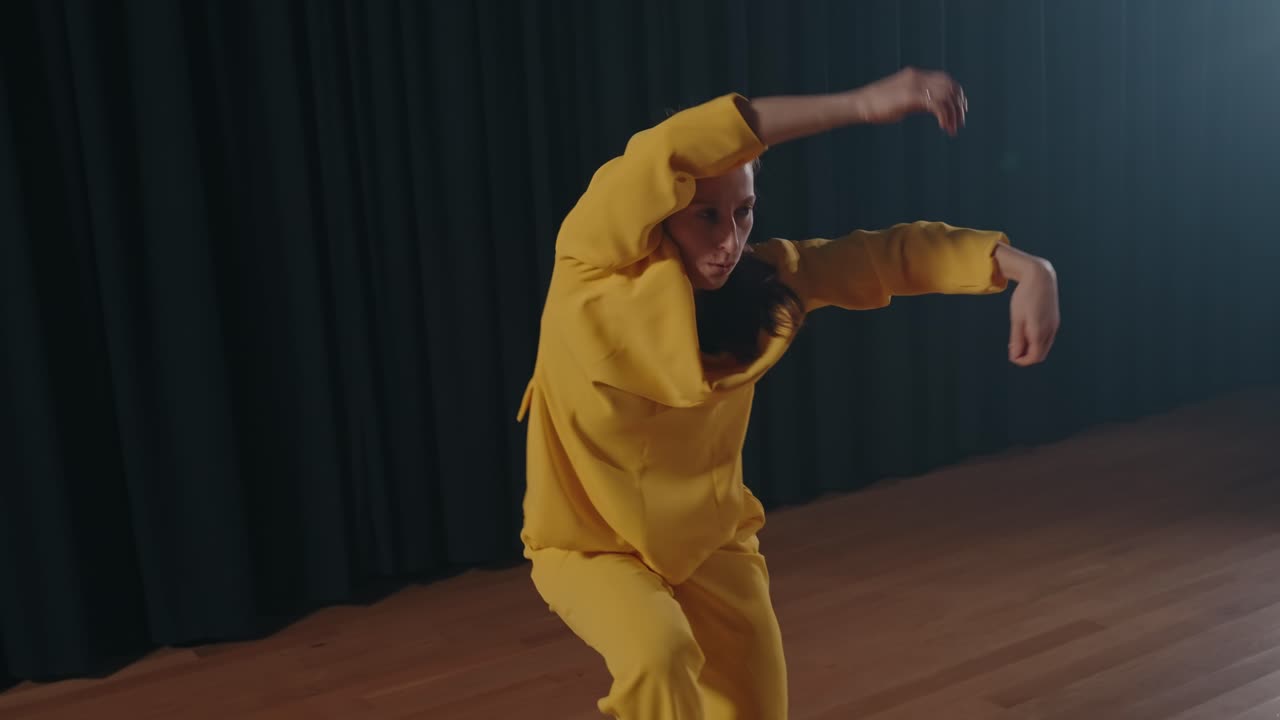 Contemporary dancer in yellow suit moves with intensity under stage lighting