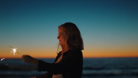 young woman playing with sparklers on beach at sunset celebrating new years eve waving sparkler fireworks enjoying independence day celebration by the sea
