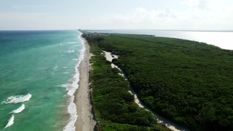 still shot of hutchinson island from 400 feet, atlantic ocean on the left, indian river on the right, with cars and trucks traveling down dirt road, and wonderful white capped waves and blue waters