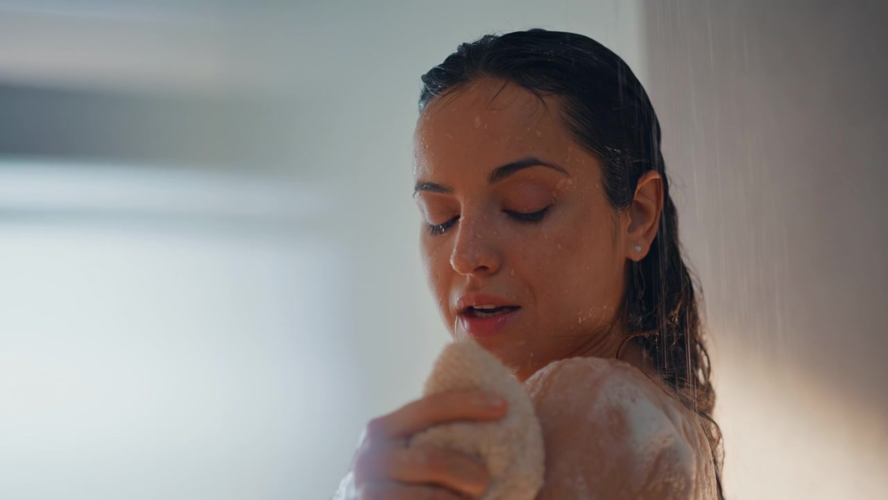 Woman washing shoulder loofah sponge shower. Closeup relaxing foam skincare.