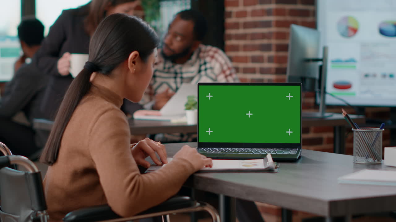Donna asiatica con disabilità che usa il greenscreen su un laptop
