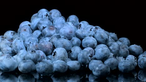 rotate of blueberries on black glass with reflection. close-up, camera rotation 360 degrees. bog bilberry, bog blueberry, northern bilberry or western blueberry (vaccinium uliginosum)