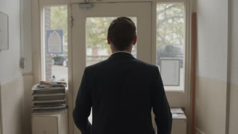 un joven enderezando su traje antes de salir