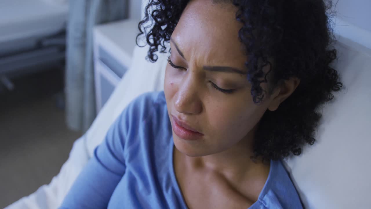 Portrait of african american female patient lying on hospital bed feeling pain