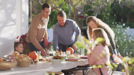 video of happy caucasian parents, daughter and grandparents sitting at outdoor table for family meal