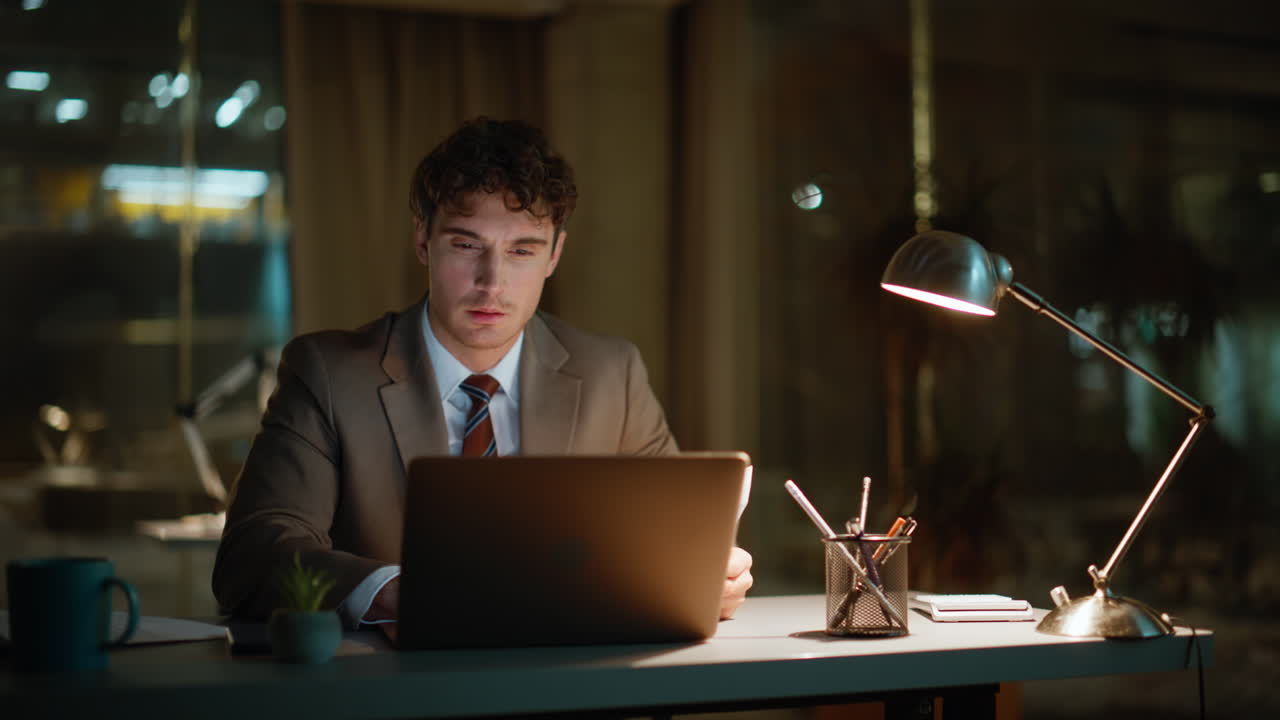 Company manager working evening office under lamp light. Businessman pondering