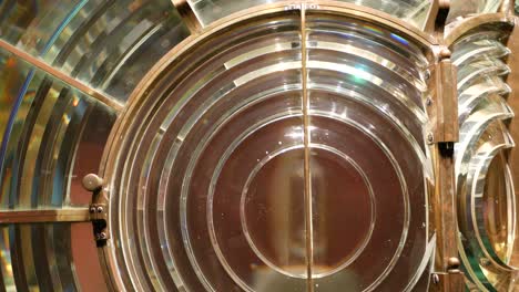 fresnel lens with brass structure, nautical lighthouse tower. detail of the glass lantern with rainbow spectrum. system of lamps and lenses to serve as a navigational aid. old sea searchlight beacon.