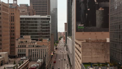 Forwards-reveal-shot-of-street-with-various-heights-of-buildings-around.-Fly-between-multi-storey-office-blocks.-Dallas,-Texas,-US