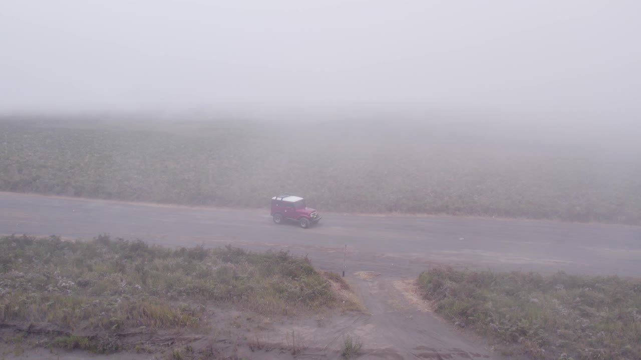 ⁇ 은 지프가 낮은 구름과 함께 브로모 산에서 모래의 바다를 통해 운전