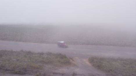 un jeep rojo conduce a través de un mar de arena en el monte bromo con nubes bajas, antena