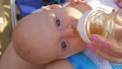 bebé acostado en el regazo de la madre y bebiendo de la botella