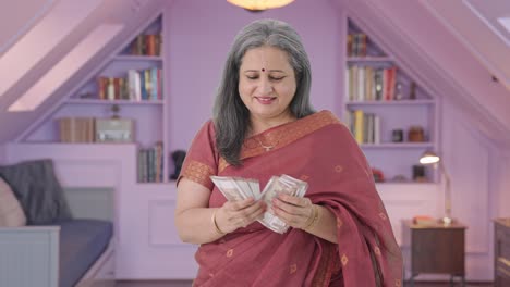 una anciana india feliz contando dinero.