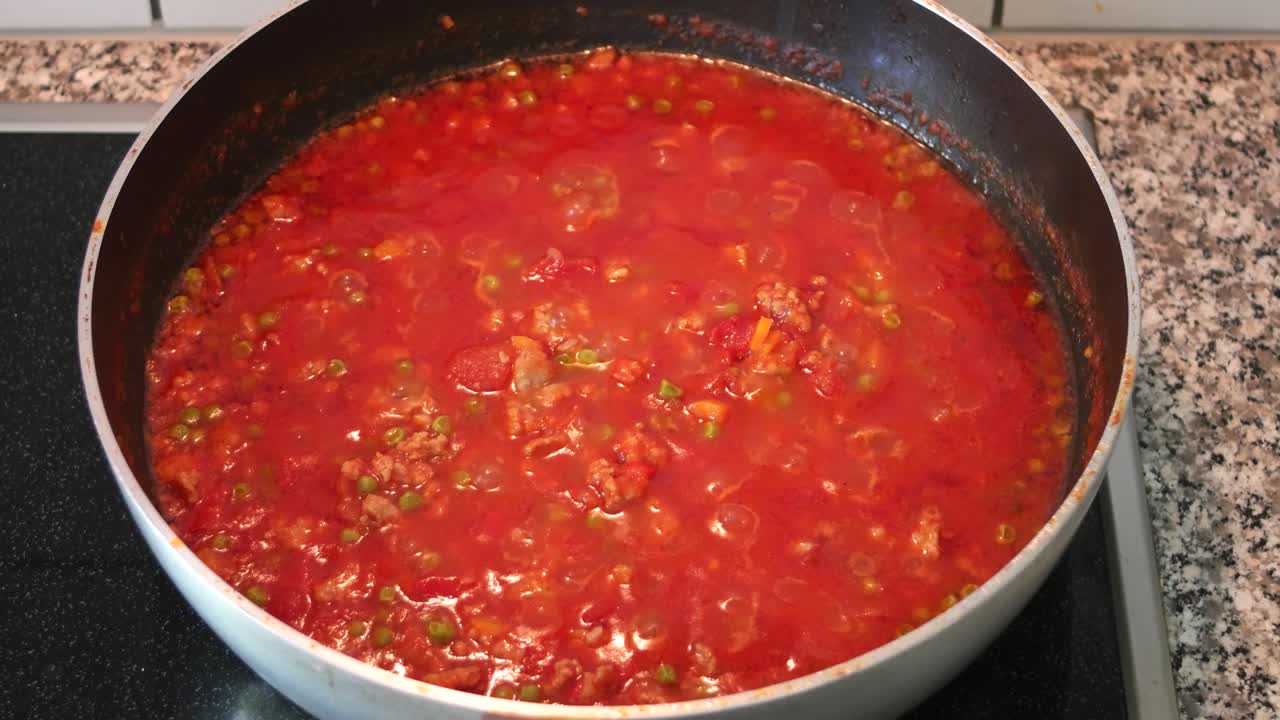 salsa de pasta de tomate casera hirviendo a fuego bajo en una sartén. disparo deslizante de cerca. en tiempo real, sin gente