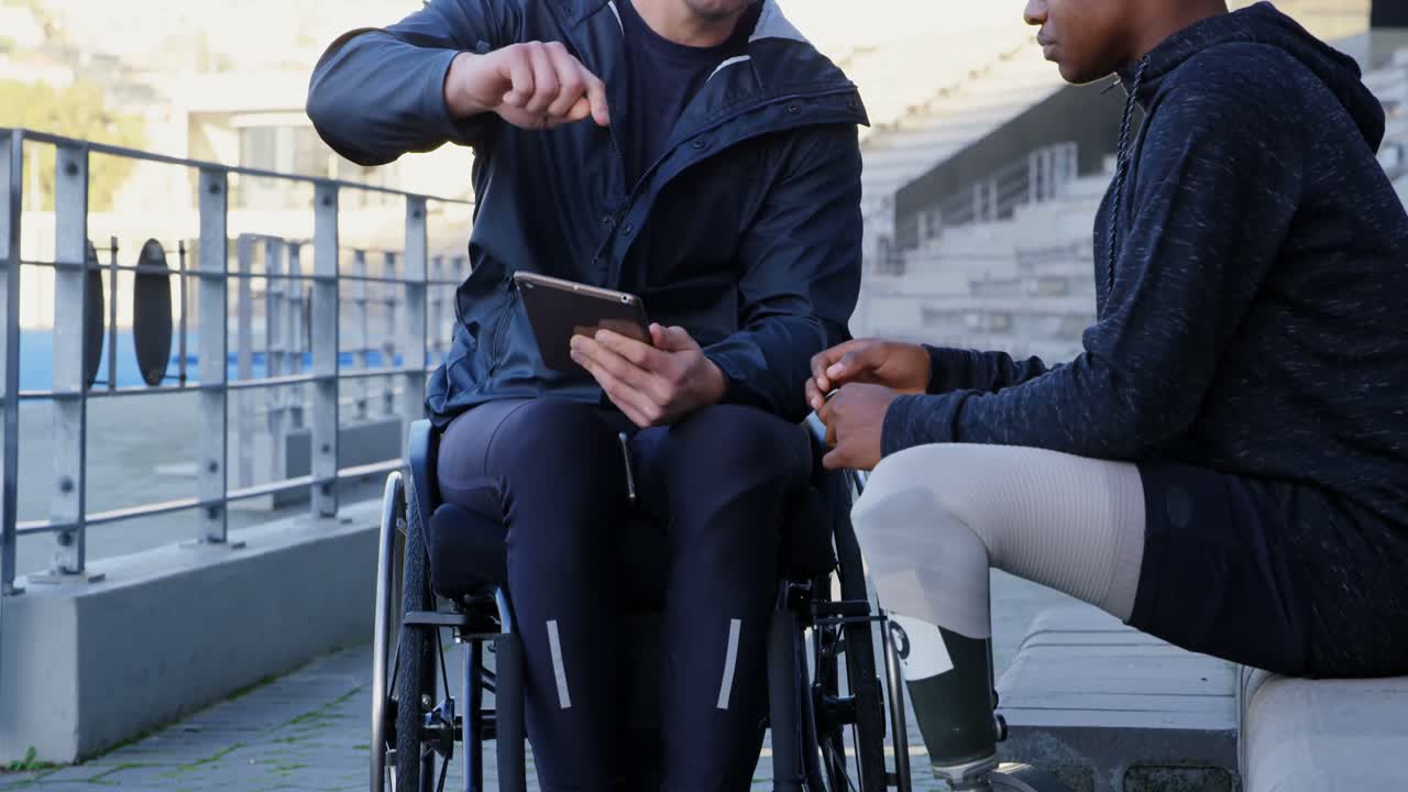 Due atleti disabili che discutono su un tablet digitale 4k
