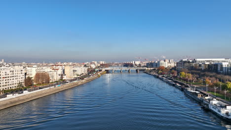 Above-Seine-River:-Paris,-Île-de-la-Jatte,-La-Défense,-barge-under-clear-skies.