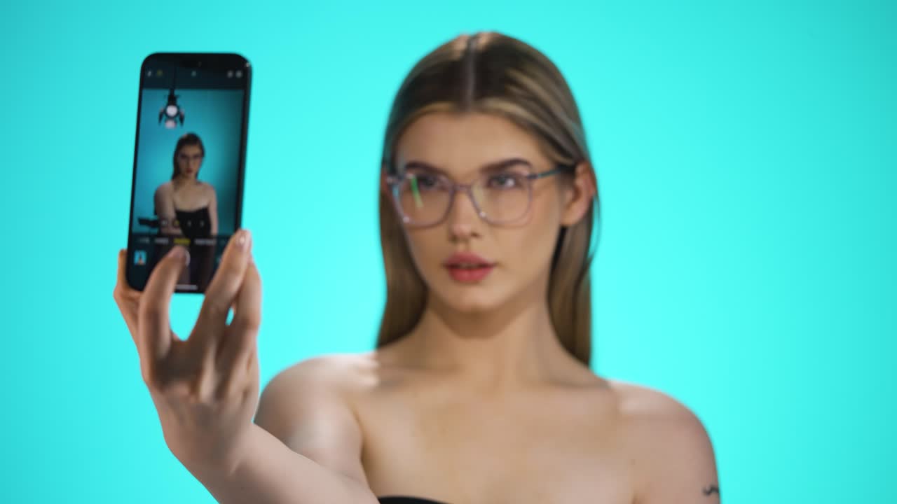 mujer rubia caucásica con gafas toma una foto selfie de su torso croma de fondo, mujer atractiva