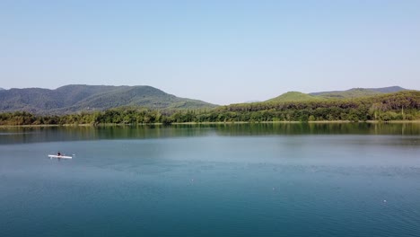 vista aérea sobre un lago natural con un remero disfrutando de un día soleado en este hermoso paisaje panorámico de la campiña española