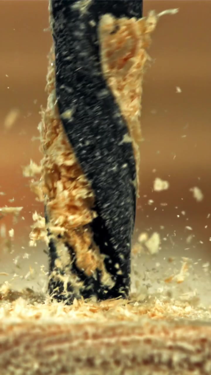Macro inquadratura di una punta da trapano che fora il legno, creando segatura
