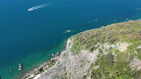 drone footage of a cliff with turquoise mediterranean water in italy.
