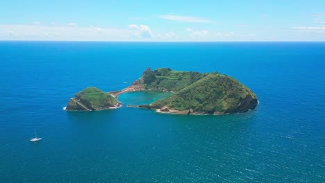 vila franca islet surrounded by clear blue waters with a sailboat nearby in são miguel azores