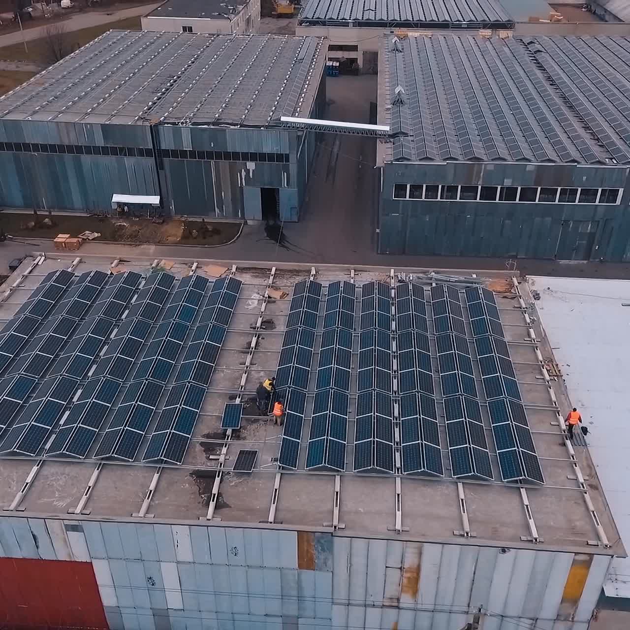 Installing solar panels on the foof of plant or factory. Additional source of electricity. Green energy. Video from the top