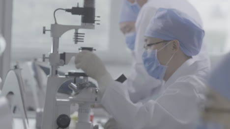team of scientists working in modern laboratory, examining samples, recording data. researches virus, working with microscopes pipettes to develop vaccine, surrounded by various scientific instruments