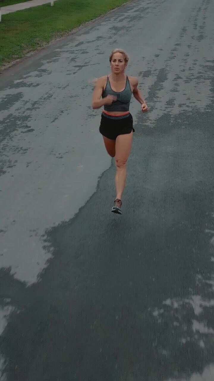 Young Woman Jogging on Wet Asphalt Road