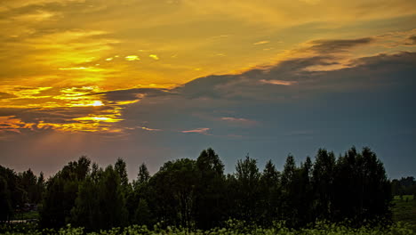 Una-Puesta-De-Sol-Dorada-Y-Un-Paisaje-Nuboso-Sobre-La-Silueta-De-Un-Bosque---Lapso-De-Tiempo