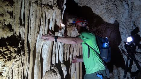 un hombre en una cueva toca estalactitas como un instrumento musical