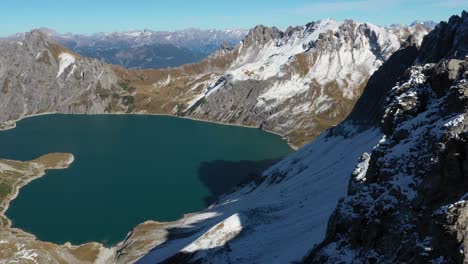 toma aérea de un hombre parado al borde de un acantilado pequeño y estrecho, con vistas al asombroso paisaje frente a él en lunersee en suiza después de una caminata extrema hasta la cima de la montaña