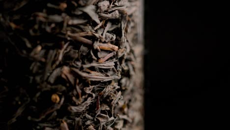 looped spinning dry black tea inside glass column close-up background