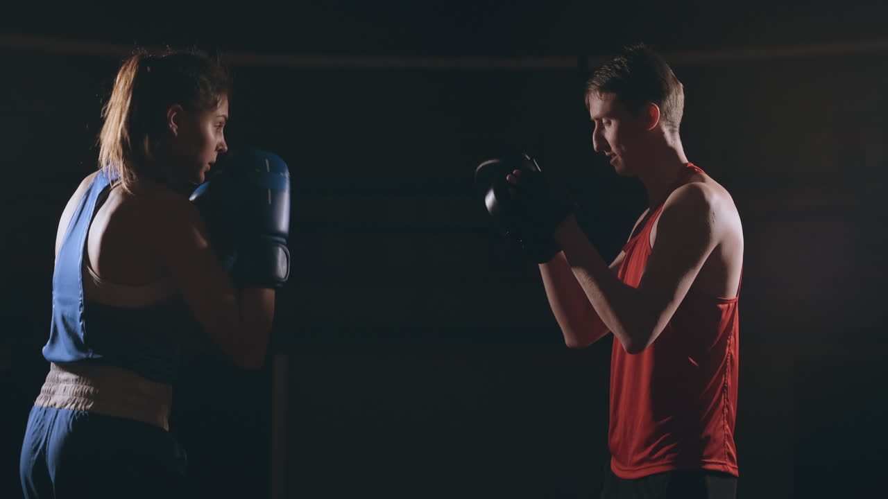 mujer adulta joven haciendo entrenamiento de kickboxing con su entrenador.