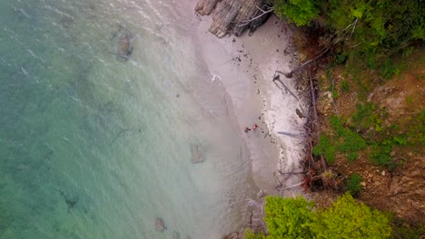 Luftbild-Von-Oben-Auf-Ein-Paar,-Das-An-Einem-Abgelegenen-Buchtstrand-Entlang-Geht