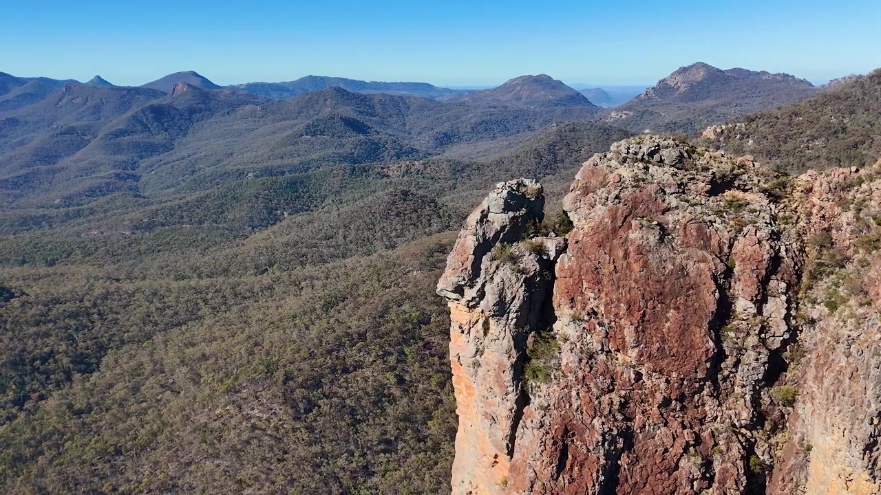 Ampia ripresa aerea di guglie di roccia vulcanica e catene montuose nel Parco Nazionale Warrumbungle, Australia.