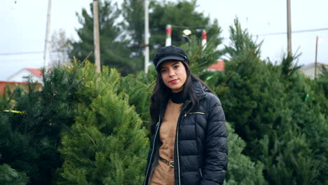 Una-Mujer-Hermosa-Con-Un-Espíritu-Navideño-Feliz-Sonriendo-Mientras-Compra-árboles-De-Navidad-Festivos-De-Abeto-Douglas