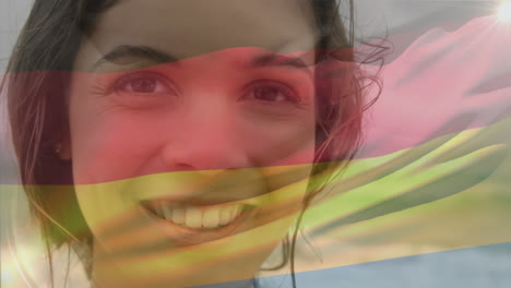 video compuesto de agitar la bandera de alemania sobre el retrato de una mujer caucásica sonriendo en la playa