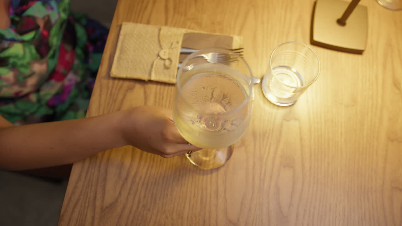 Woman Hand Holding Glass Of Wine On The Restaurant Table During Dinner