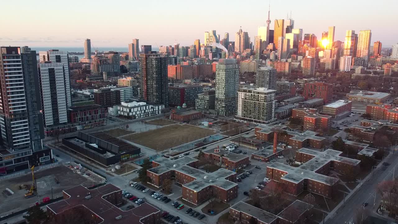 Drone reveal shot of Regent Park Toronto in the early morning sunrise flying towards downtown.