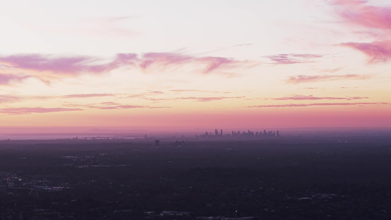 Imagens aéreas impressionantes capturam o Croydon Park ao pôr do sol, com um céu vibrante pintando tons de rosa e laranja sobre o horizonte distante da cidade. Vista estética do horizonte na hora dourada.