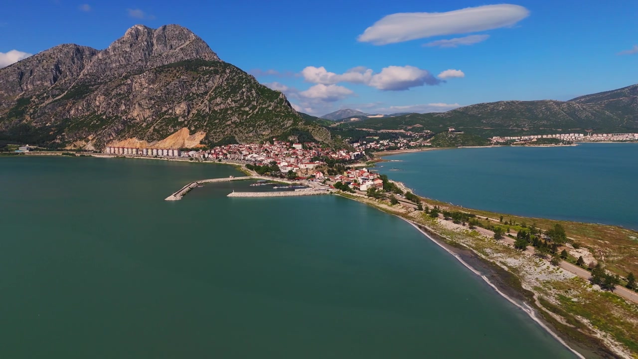 Luftfoto af Egirdir-søens turkise kystfarvande, der omgiver den beboede halvø. Majestætisk bjergryg og landsbyudsigt ved søen i Anatolien, Tyrkiet