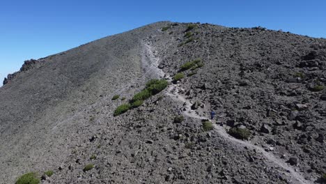 Excursionista-Caminando-Por-Un-Sendero-Hacia-La-Cima-De-Una-Montaña-Rocosa-Y-árida