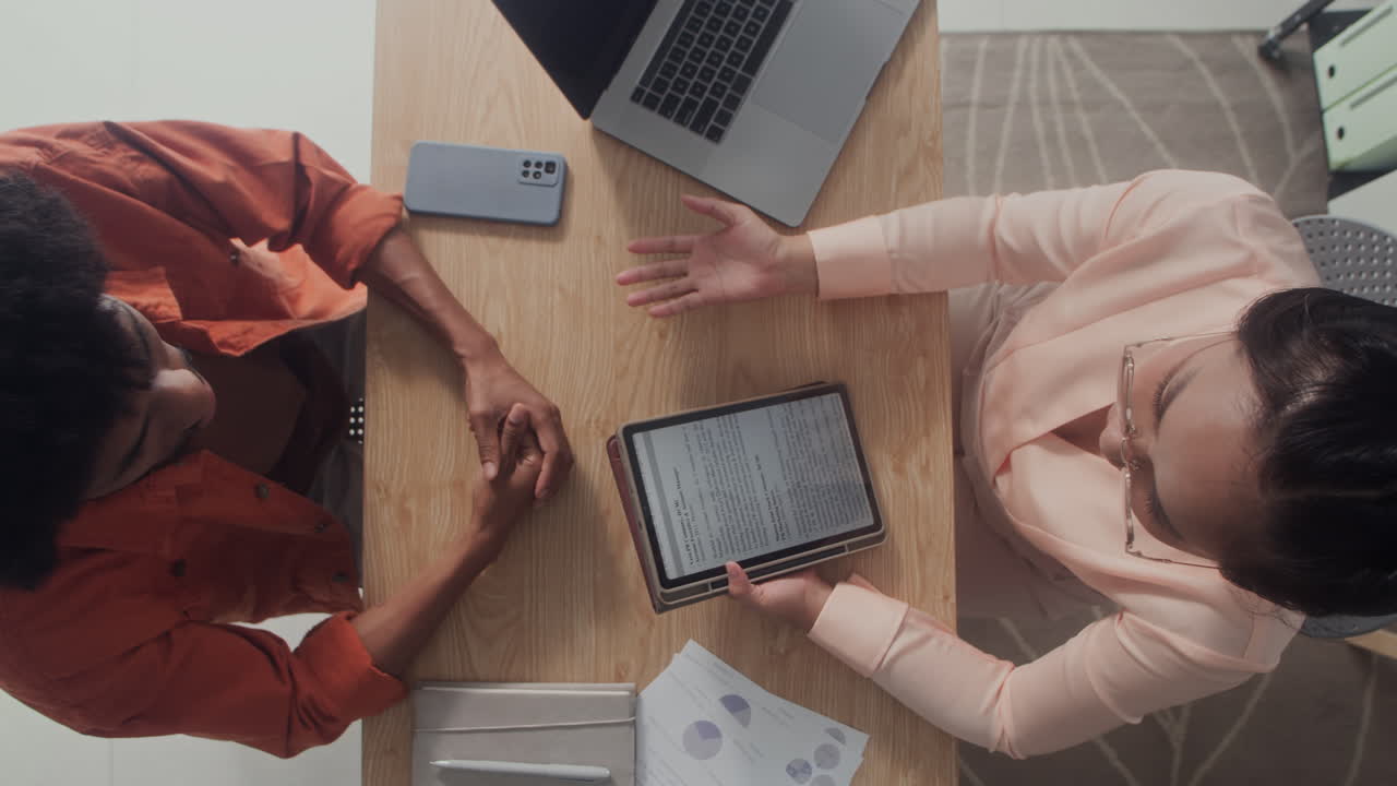Diverse Coworkers Using Tablet and Communicating at Office Table Top View