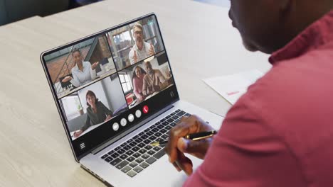 African american man using laptop for video call, with diverse business colleagues on screen