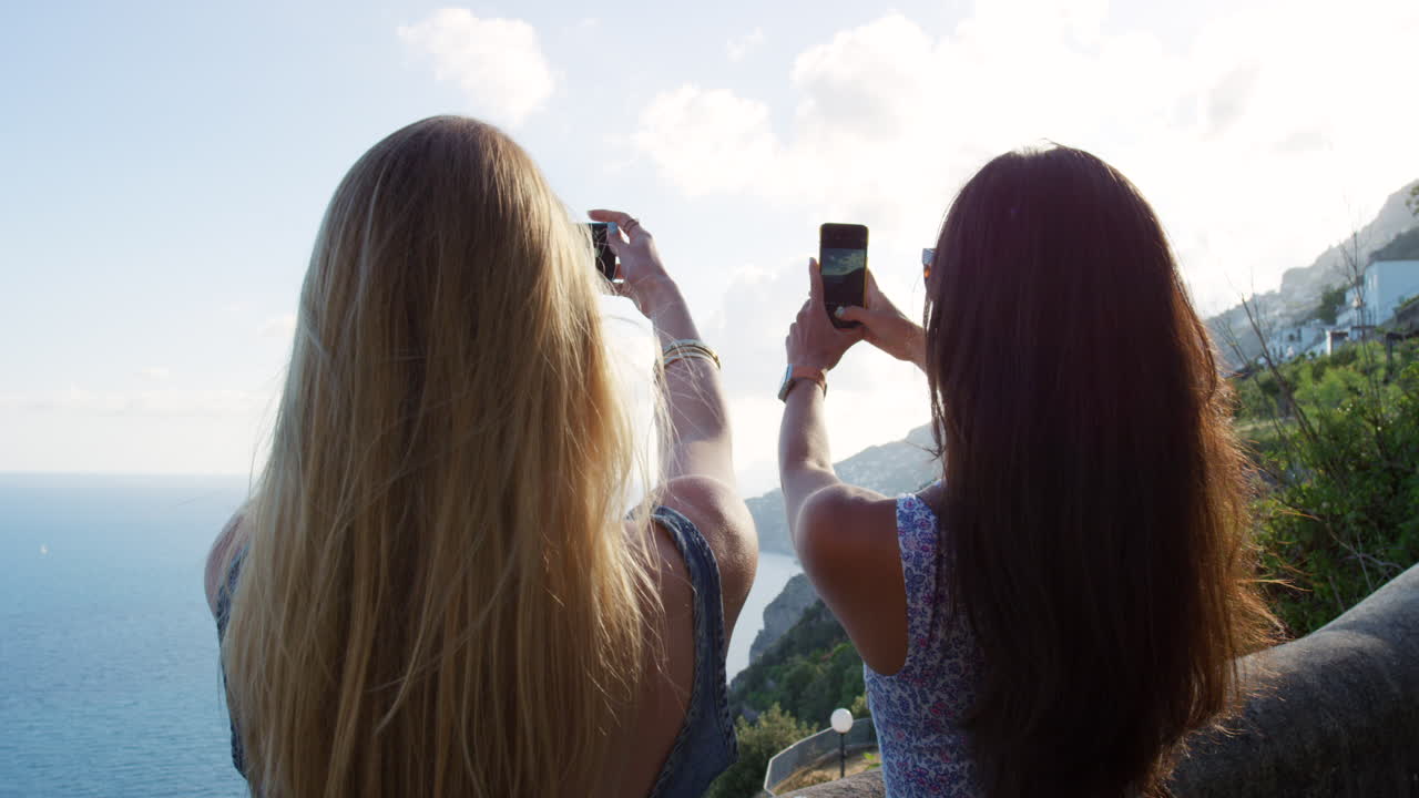 dos mujeres tomando fotos de una hermosa vista costera