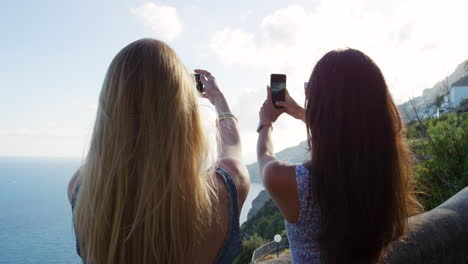 two women taking pictures of a beautiful coastal view