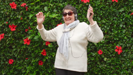 happy senior woman dancing to music in a garden