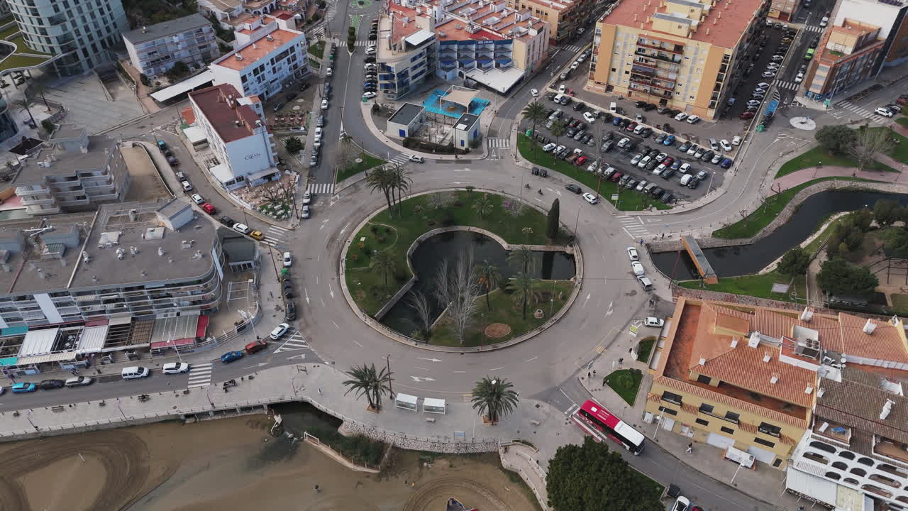 Aerial pan from Placa Constitució roundabout to nearby beach area with parked cars