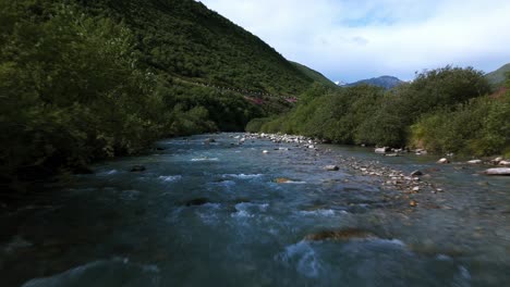 drone flying over furka pass river water stream surface in summer season, switzerland