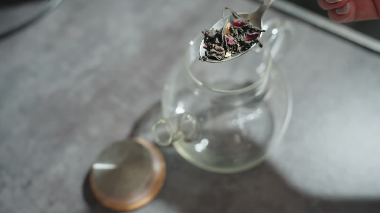 Glass Teapot With Loose Tea Leaves Settling On Base, Warm Kitchen Light, Shallow Depth, Slow Infusion, Steam Haze, Reflective Surface, Close Macro On Leaf Texture And Amber Tint, Cozy Meditative Mood