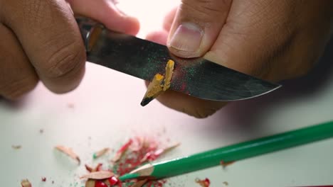 Footage-of-hands-slowly-sharpening-a-pencil-and-some-coloured-pencils-with-a-sharp-knife